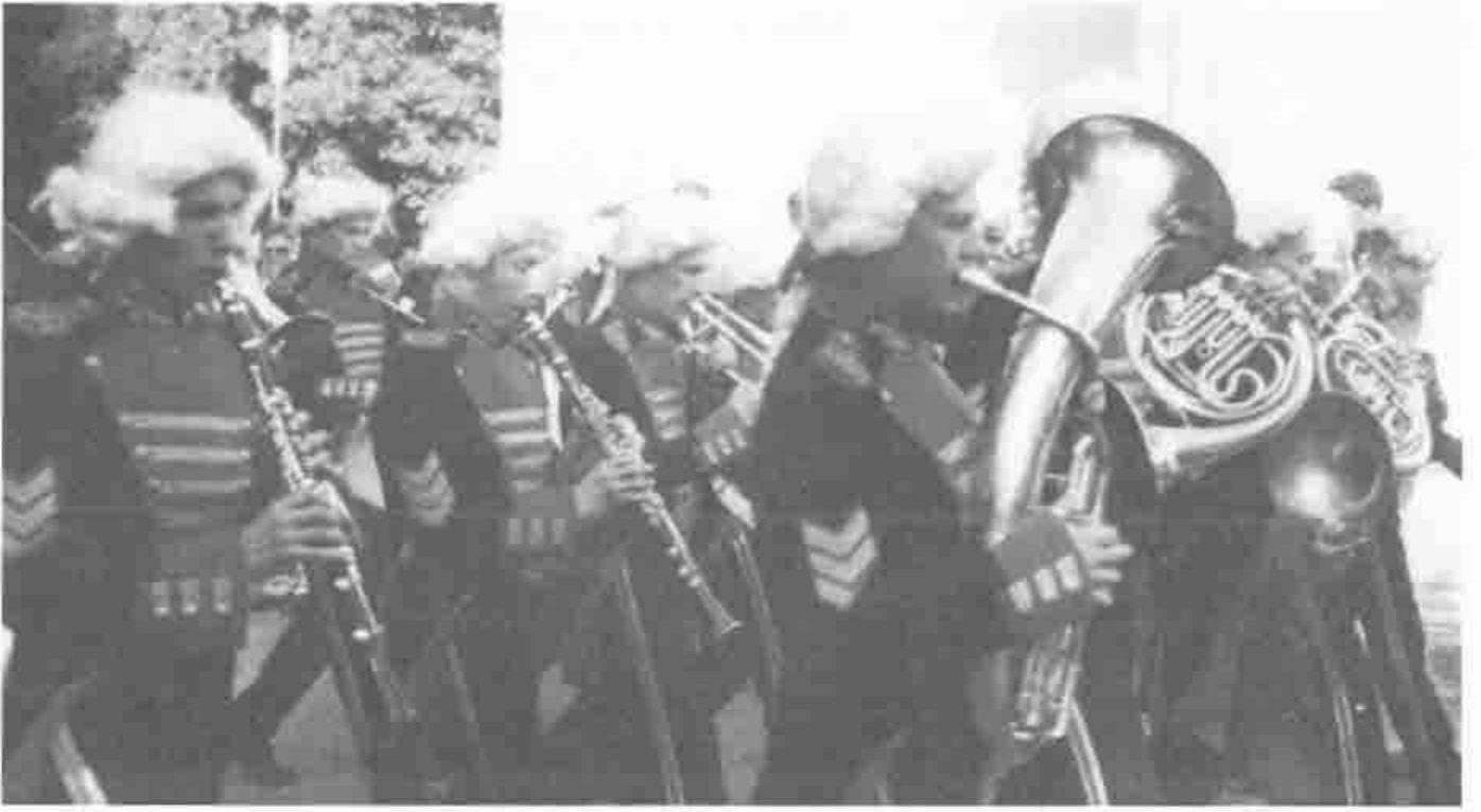 Bandsmen in white wigs and braided eighteenth-century uniforms playing clarinets, horns and a tuba