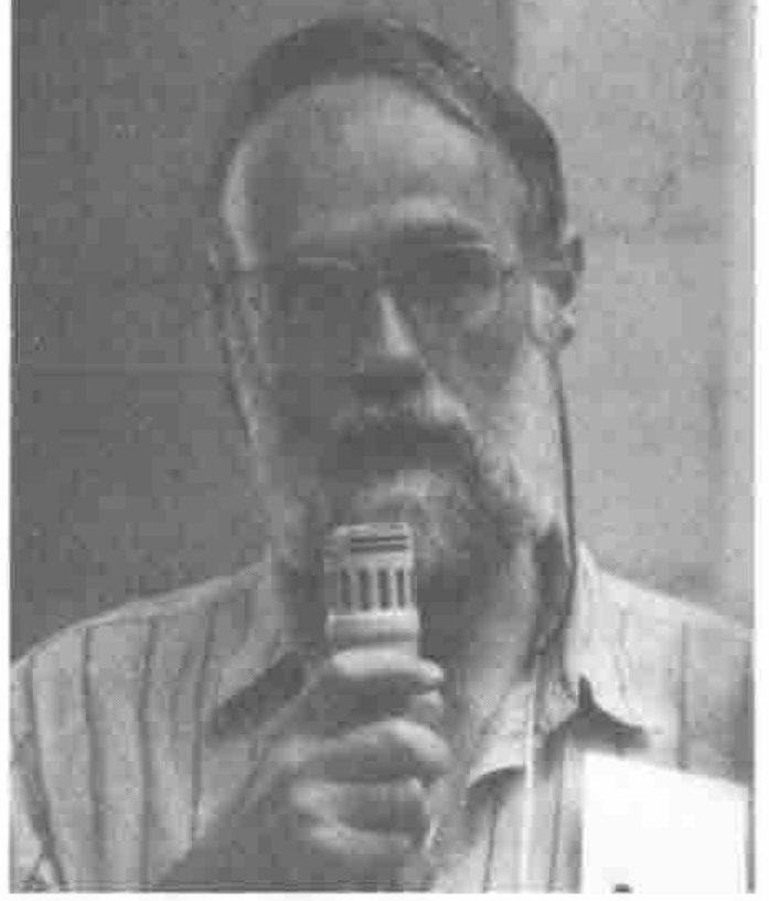 A bearded man in glasses speaking into a microphone