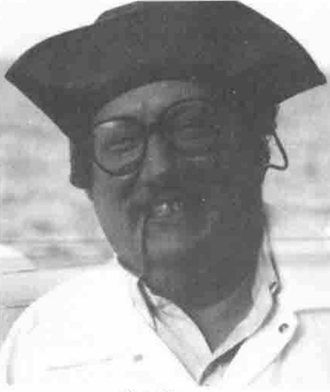 A man in glasses and a tricorn hat, smoking a pipe