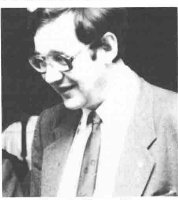 A man in glasses, smiling, looking down