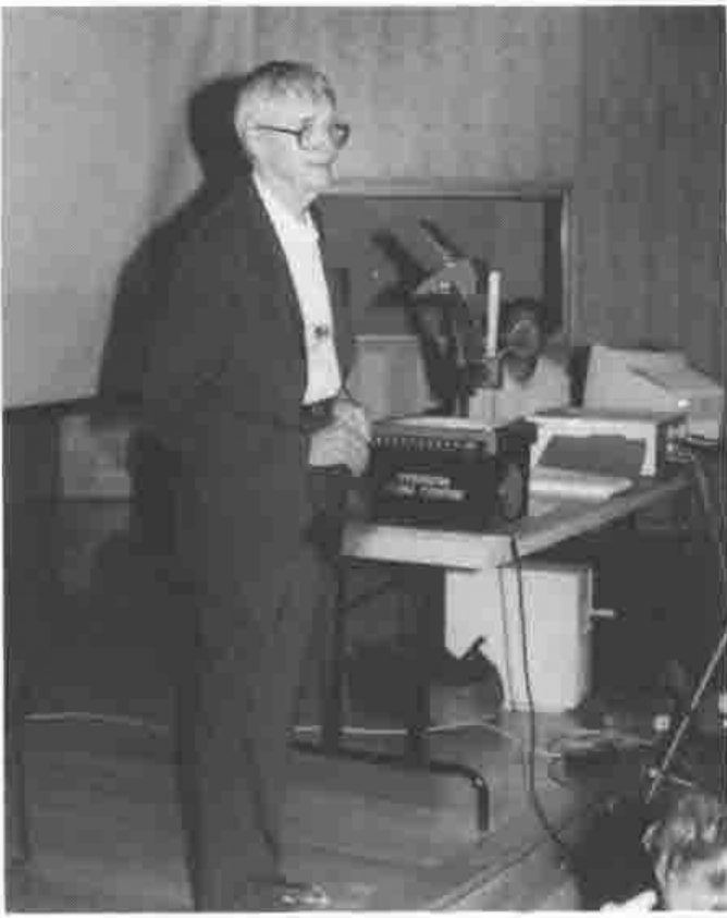 Ken Iverson standing beside an overhead projector