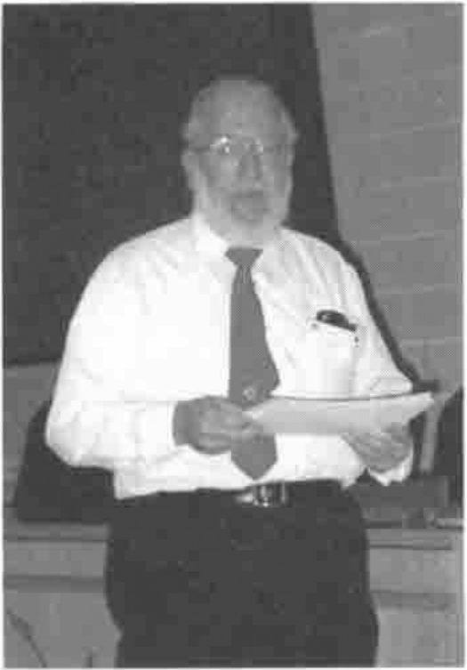 Jack Rudd, bearded, holding papers and speaking
