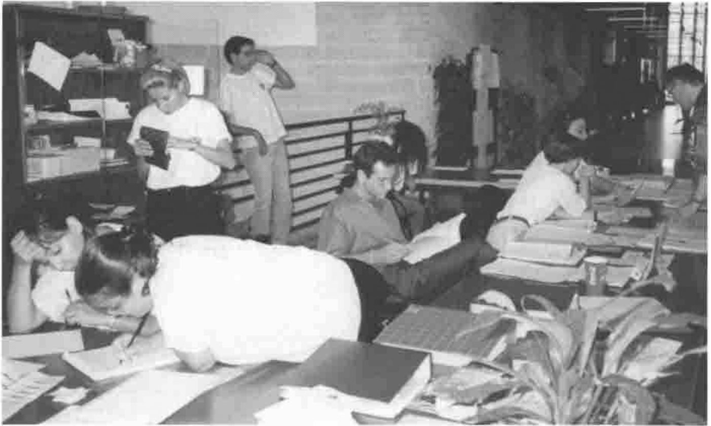 The front desk: staff reading and writing at tables covered in papers