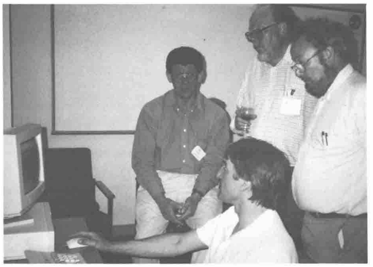 Four men around a computer: one seated at the keyboard, three watching
