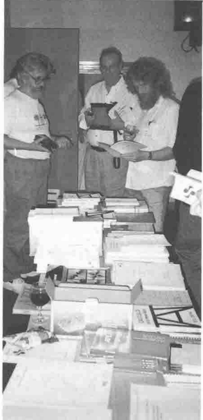 Three people browsing a table of books and papers
