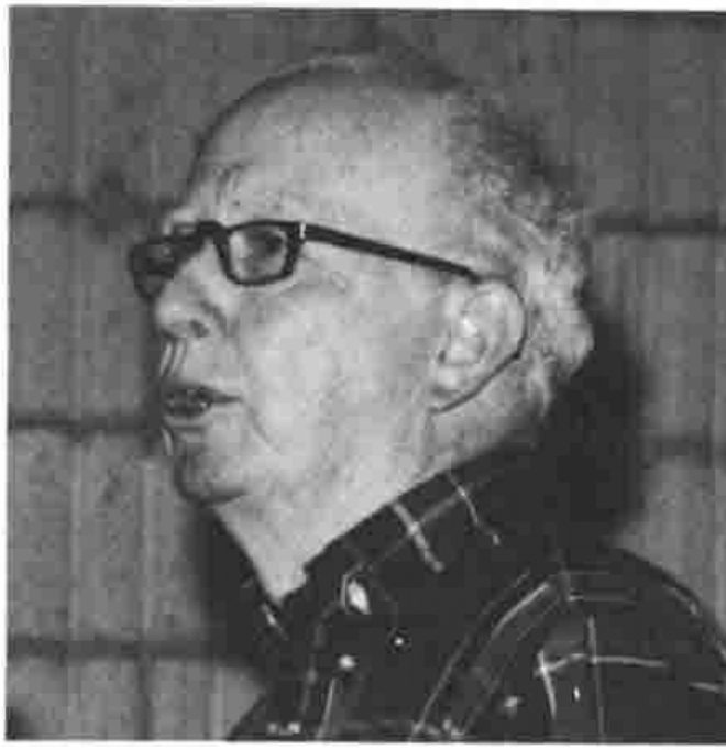 Photograph of Eugene McDonnell speaking, in profile, wearing glasses and a checked shirt