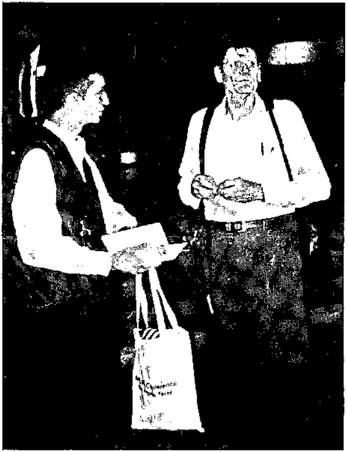 Photograph of Jon Sandles talking with Phil Benkard, who wears braces and holds a conference bag