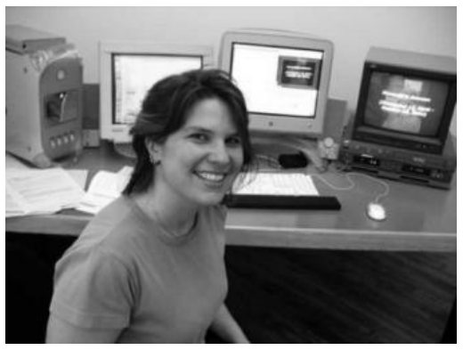 Photograph of Catherine Lathwell at a desk with computer and video monitors