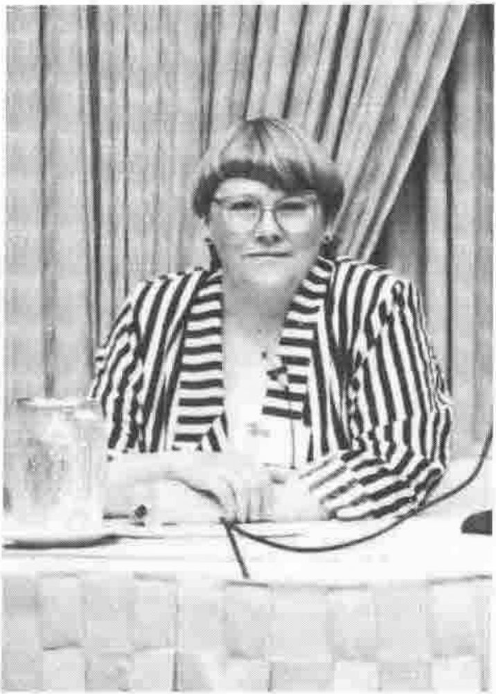 A woman in glasses and a striped jacket seated at a table