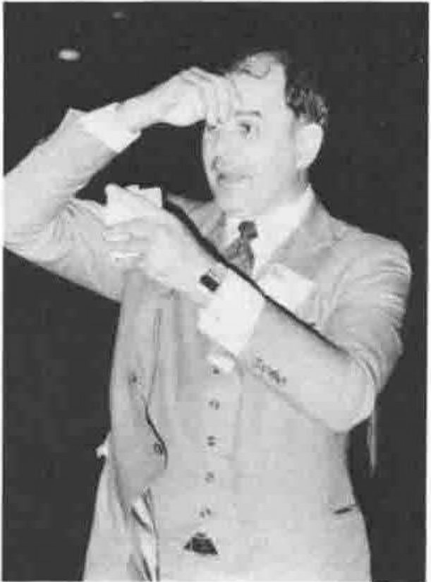 A man in a suit holding a handkerchief to his forehead and looking to one side