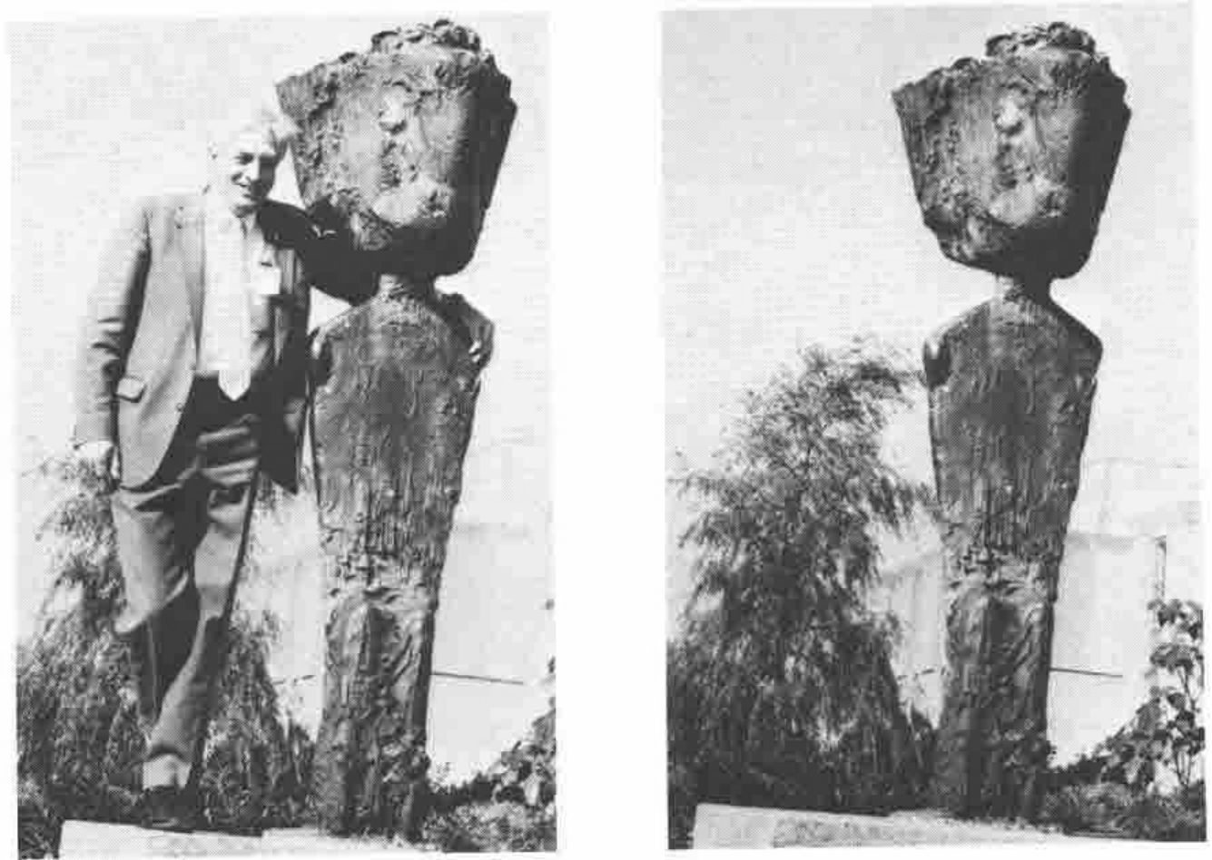 Two photographs of a tall rough-cast sculpture in a garden: a narrow standing figure balancing a huge block-like head. On the left a smiling man in a suit and tie leans against it, one arm up beside the head; on the right the sculpture stands alone