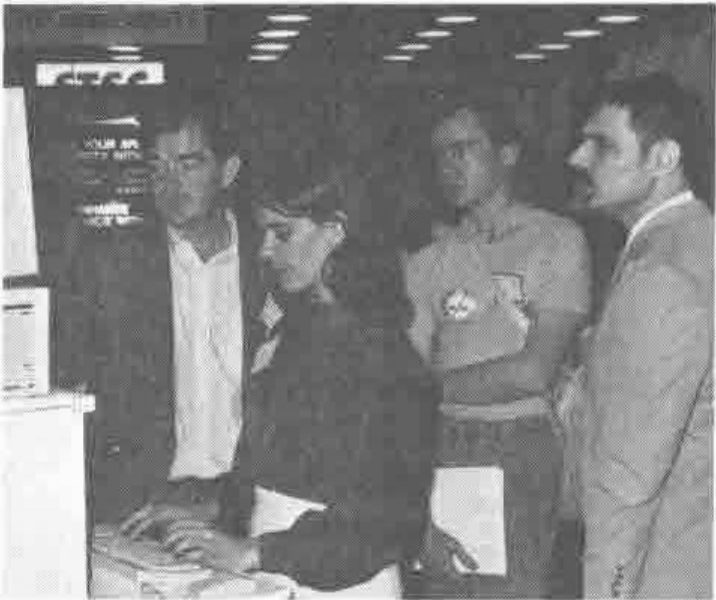 Photograph of a woman at a keyboard with three men watching