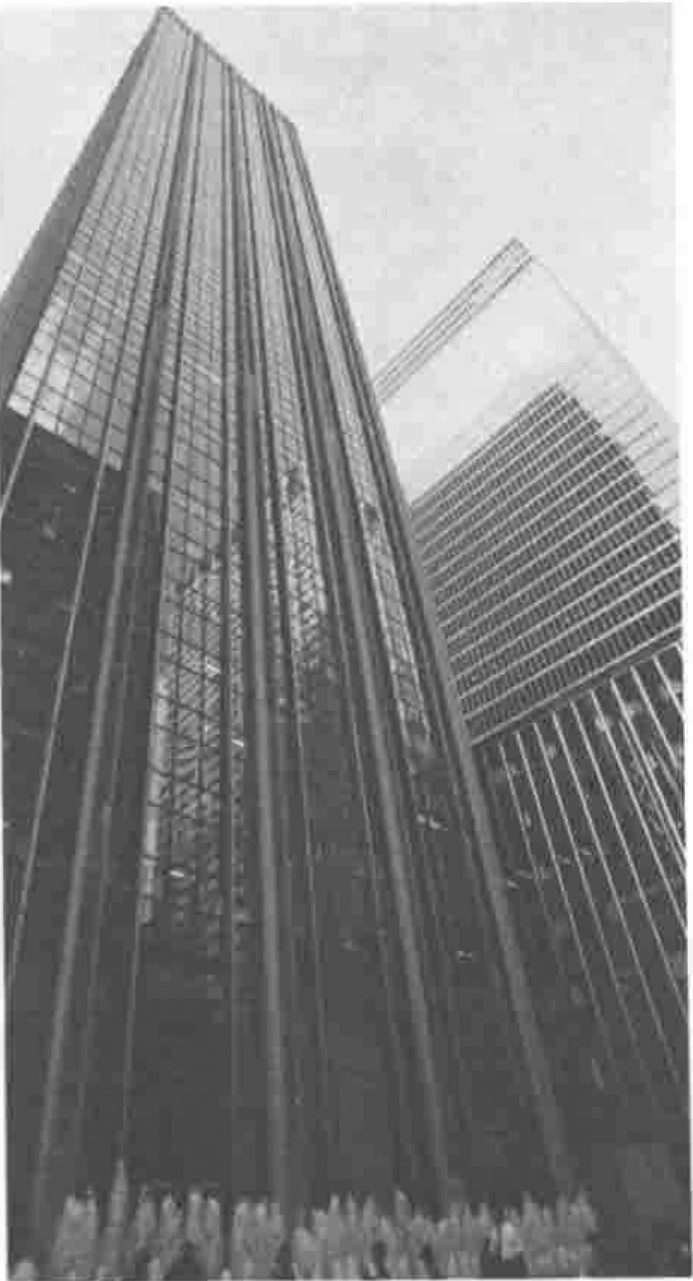 Photograph looking up at a glass-fronted skyscraper, with fountains at its foot