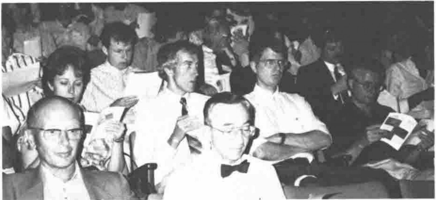 Delegates seated in an auditorium, some reading programmes