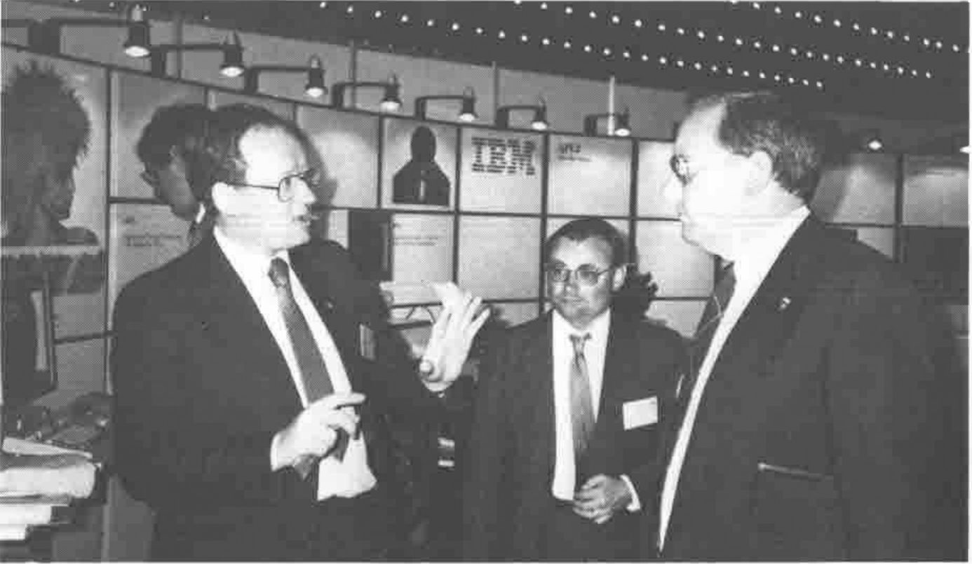 Three men in suits talking in front of an IBM exhibition stand
