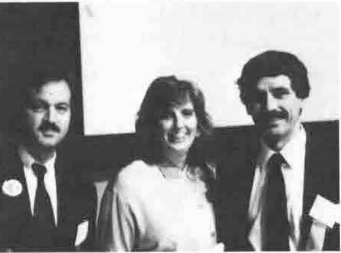 Two men in suits and a woman between them, smiling