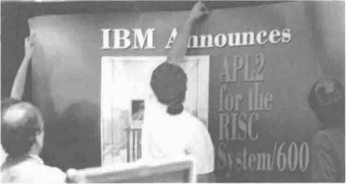 People putting up a large banner reading “IBM Announces APL2 for the RISC System/600”, its last letters cut off