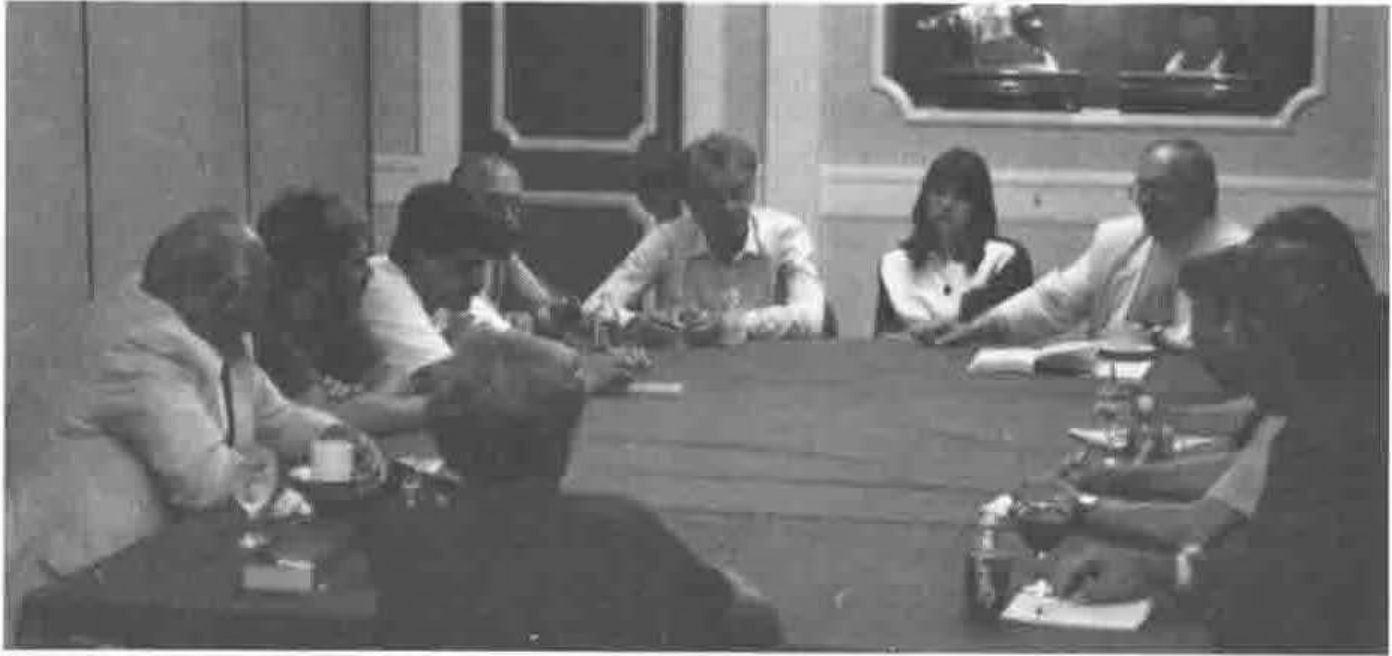 About ten people seated around a large table in a panelled room