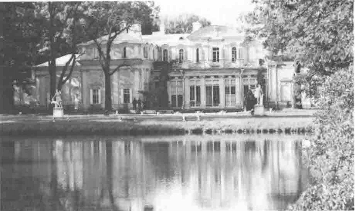 A baroque palace reflected in a lake, framed by trees