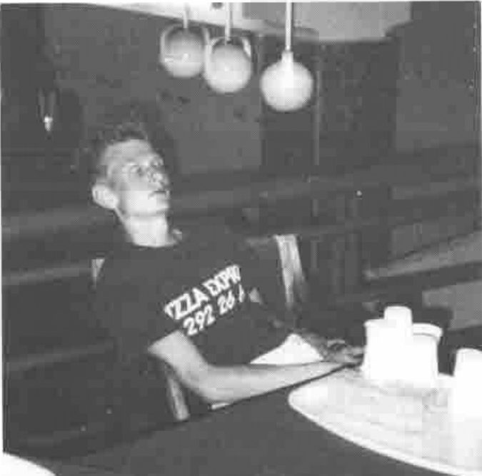 A young man in a Pizza Express T-shirt slumped asleep at a table