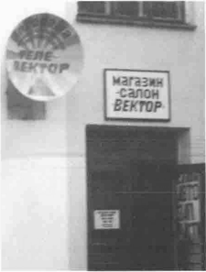 A shop doorway beneath a sign reading “Магазин-салон ВЕКТОР”, with a satellite-dish sign reading “ТЕЛЕ-ВЕКТОР”